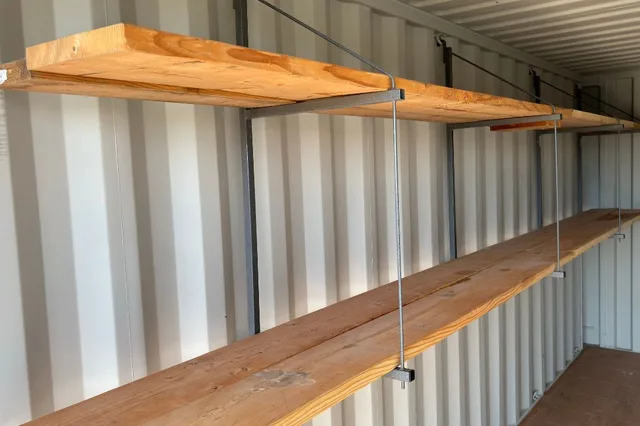 Wall-mounted shelving brackets installed in a shipping container